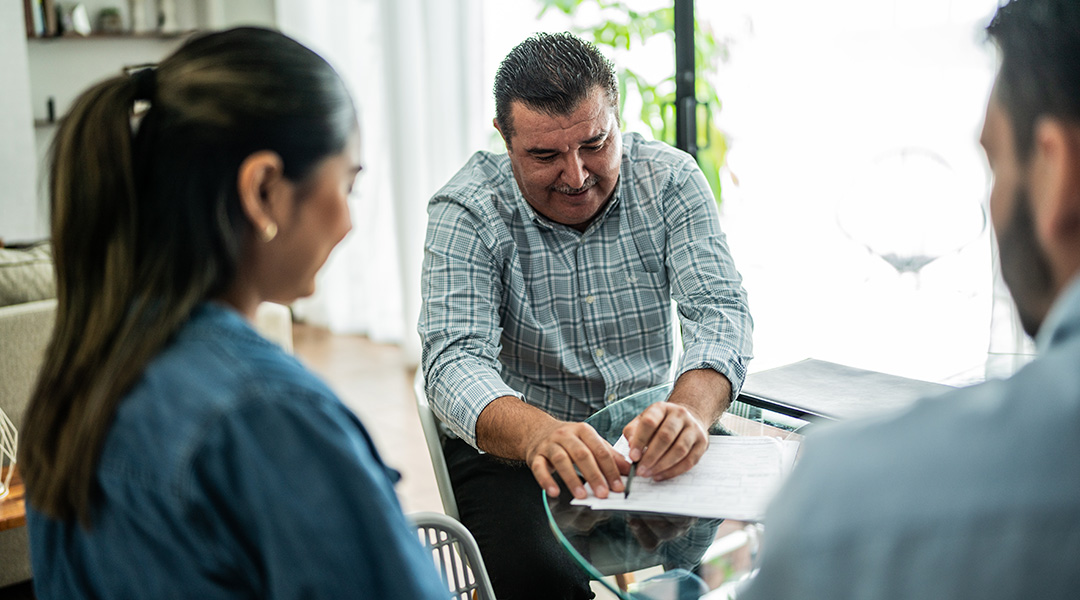 A man explaining a document to two other people
